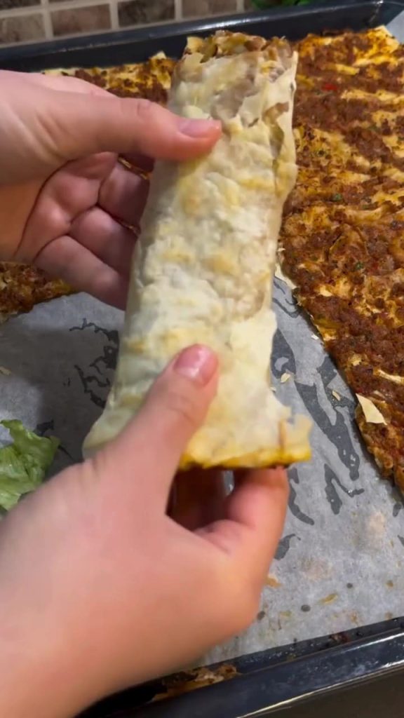 A stack of crispy Turkish lahmacun made with yufka sheets on a wooden board.