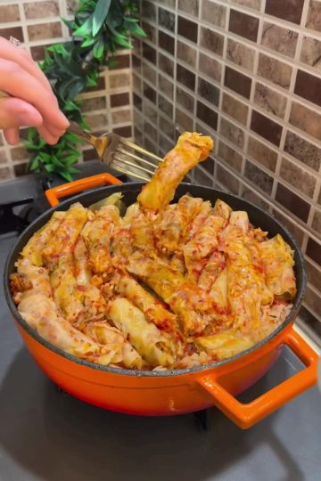 A platter of tightly rolled Turkish cabbage sarmas with red tomato sauce.