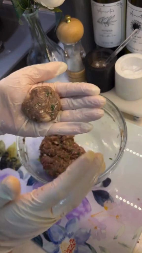 Frying round meatballs in a skillet for eggplant skewers.