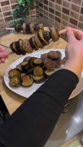 Threading fried eggplant and meatballs onto wooden skewers.