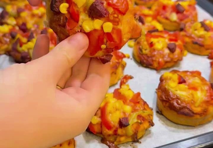 A platter of colorful mini pizzas with melted cheese and sucuk.