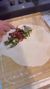 Folding a stuffed dough circle to create a gözleme.