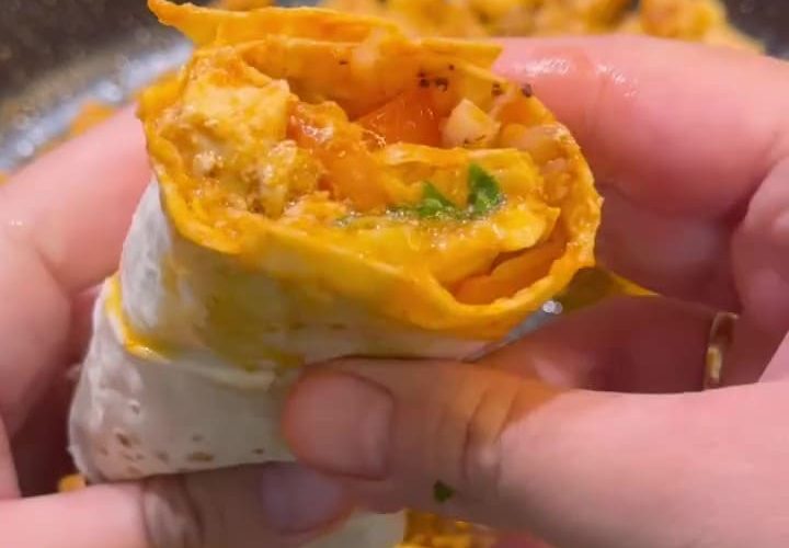 A succulent chicken tantuni wrap with tomatoes, sumac onions, and parsley on a plate.