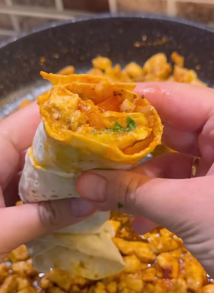 A succulent chicken tantuni wrap with tomatoes, sumac onions, and parsley on a plate.