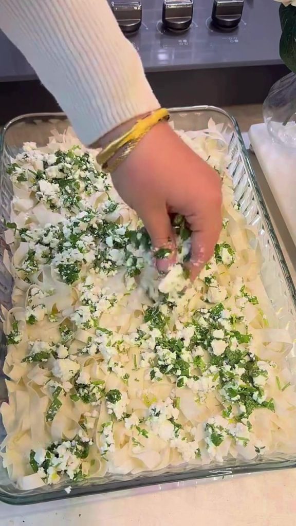 Adding a layer of feta cheese and parsley to a borek.