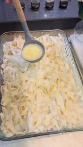 Pouring milk and egg sauce over shredded yufka.