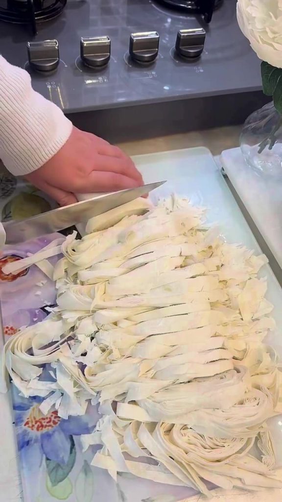 Slicing rolled-up yufka sheets into wide strips for borek.