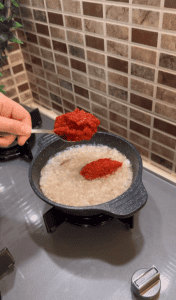 Sautéing onions and Turkish pepper paste in a skillet.