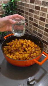 Pouring hot water over pasta and meat in a one-pot meal.