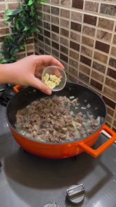 Adding tomato and pepper pastes to sautéed minced meat.