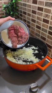 Sautéing minced beef and onions in a large pot.