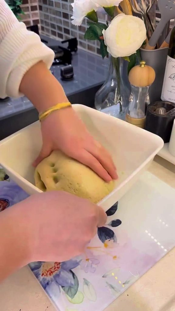 A large bowl of risen yeast dough covered with a cloth.