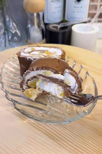 A beautiful sliced biscuit log cake filled with cream and orange pieces.