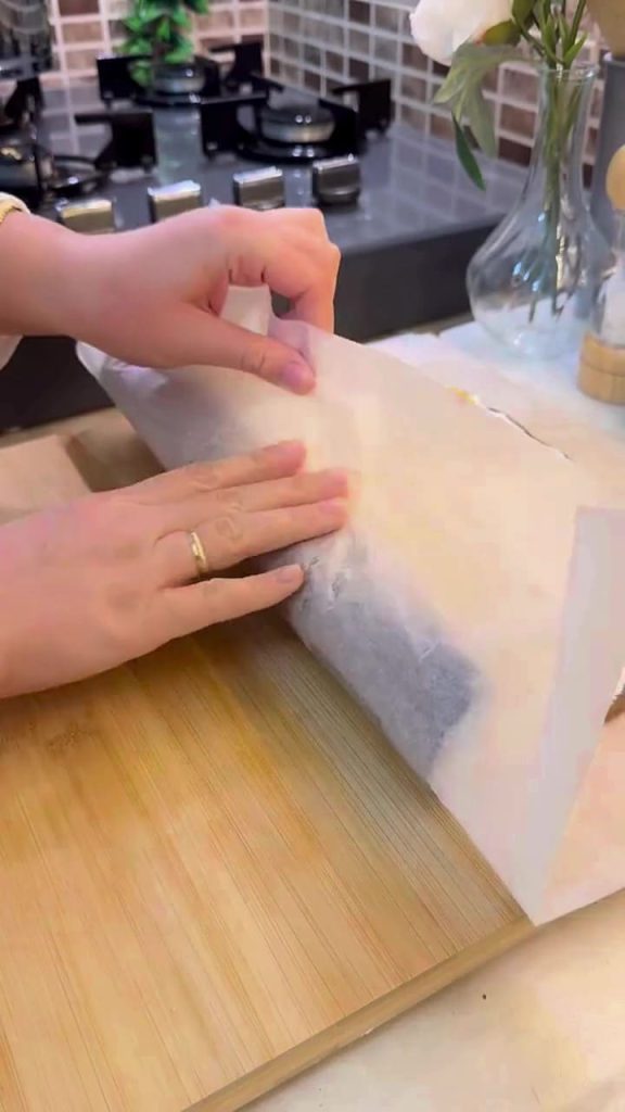 Rolling a biscuit and cream cake into a roulade shape.