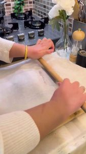 Rolling out biscuit dough between two sheets of parchment paper.