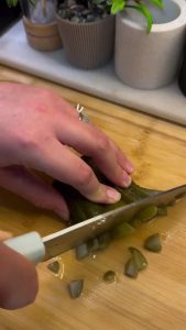 Finely chopping fresh dill and pickles for a salad.