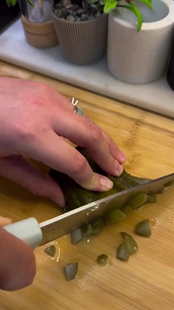 Finely chopping fresh dill and pickles for a salad.