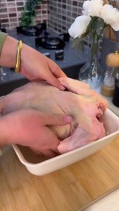Brining a whole chicken in a large bowl of saltwater.