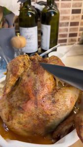 A perfectly roasted whole chicken resting on a wooden board.