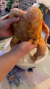 Placing a whole chicken vertically onto the tube of a cake pan.
