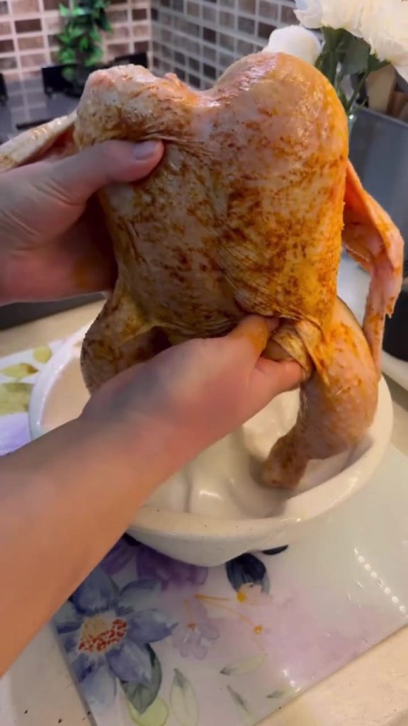 Placing a whole chicken vertically onto the tube of a cake pan.