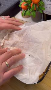 Covering the chickpea dish with wet parchment paper.