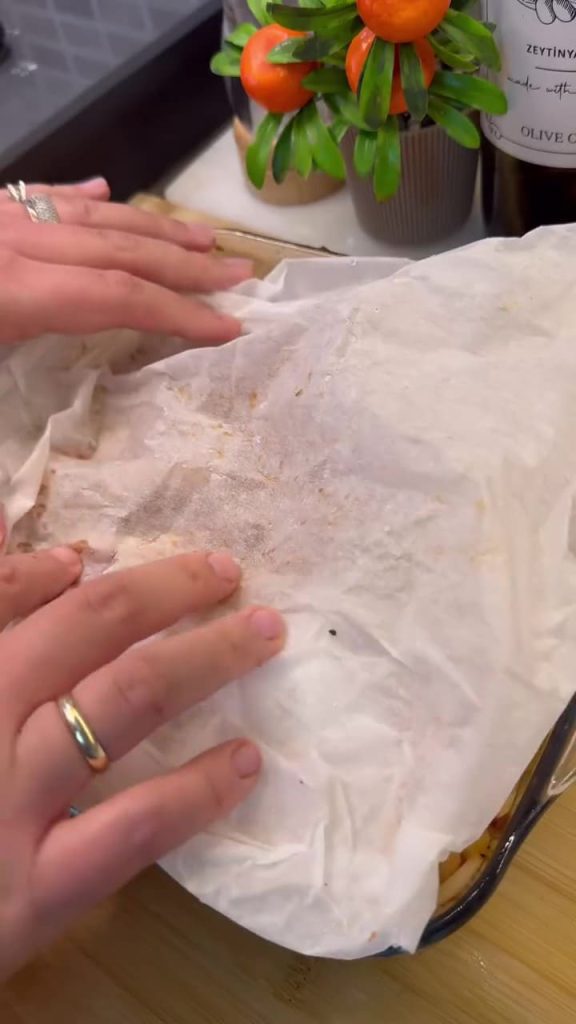Covering the chickpea dish with wet parchment paper.