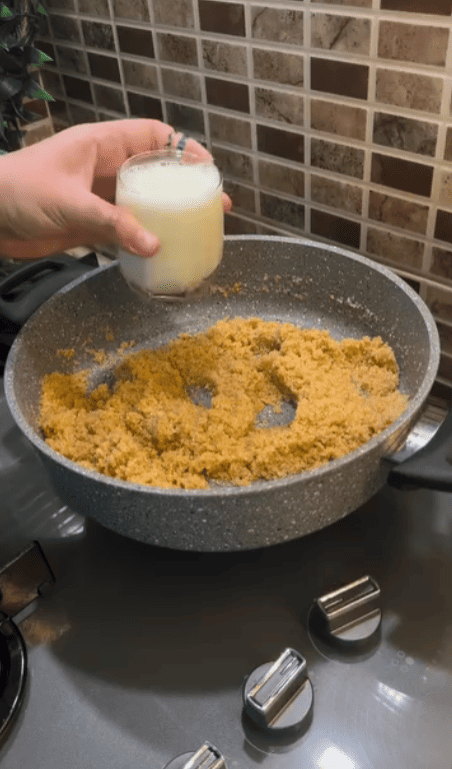 Pouring milk into a pot of roasted semolina.