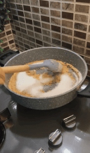 Mixing granulated sugar into roasted semolina.