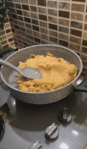 Stirring halva as it thickens and absorbs milk.