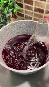 Boiling purple shalgam juice in a pot for cooking couscous.