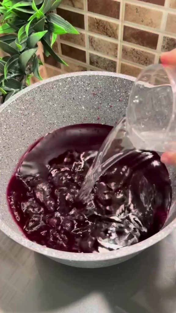 Boiling purple shalgam juice in a pot for cooking couscous.