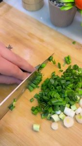 Finely dicing fresh green onions and herbs for a salad.