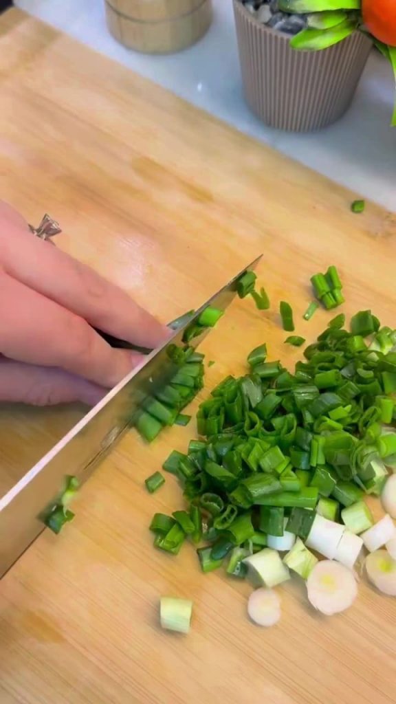 Finely dicing fresh green onions and herbs for a salad.