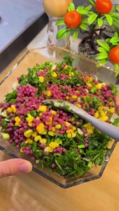 Tossing the vibrant purple couscous salad with a lemon dressing.