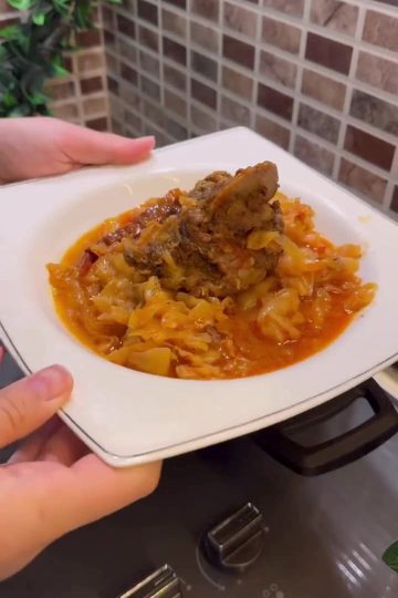 A bowl of traditional Turkish cabbage stew with large pieces of bone-in meat.
