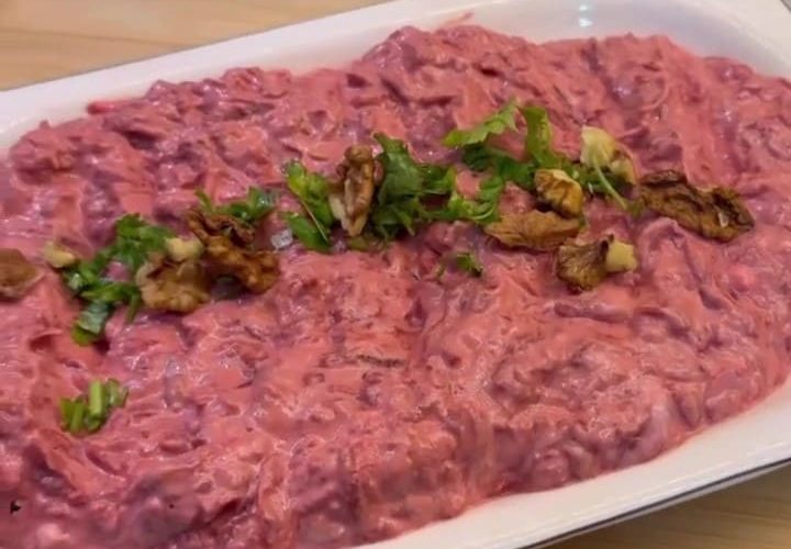 A bowl of electric pink beetroot meze topped with walnuts and parsley.
