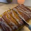 A moist slice of whole orange cake glazed with citrus syrup on a white plate.