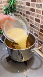 Pouring the tempered yogurt mixture into the hot soup pot.