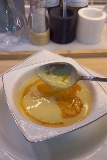 A bowl of creamy ivory-colored Çeşmi Nigar soup with a red pepper butter drizzle.