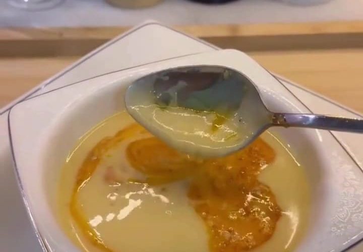 A bowl of creamy ivory-colored Çeşmi Nigar soup with a red pepper butter drizzle.