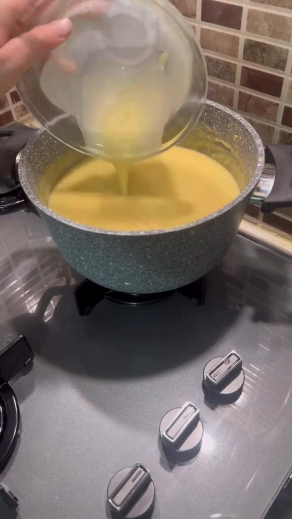 Adding milk and egg tempering to a hot lentil soup.