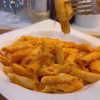 A bowl of penne pasta coated in a vibrant, creamy orange pepper paste sauce.