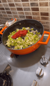 Adding Turkish pepper paste and tomato paste to sautéed onions.
