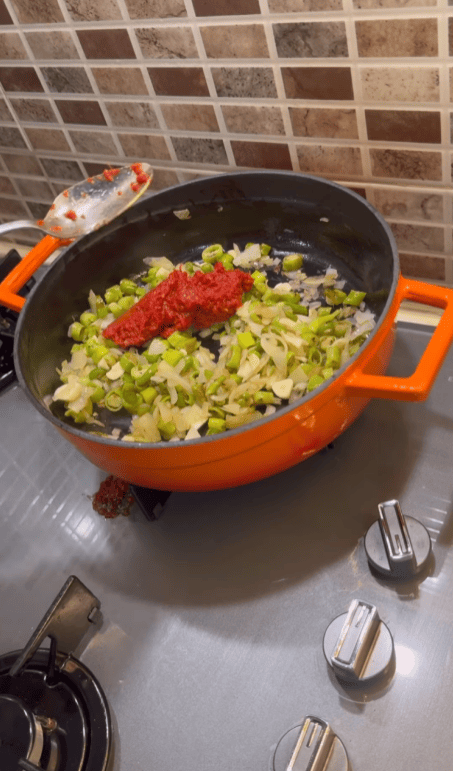 Adding Turkish pepper paste and tomato paste to sautéed onions.