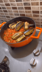 Pouring hot water over eggplants in a savory tomato sauce.