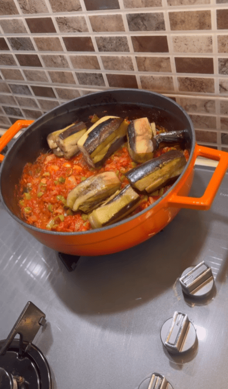 Pouring hot water over eggplants in a savory tomato sauce.
