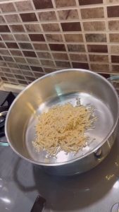 Toasting dry egg noodles in a pot with oil.