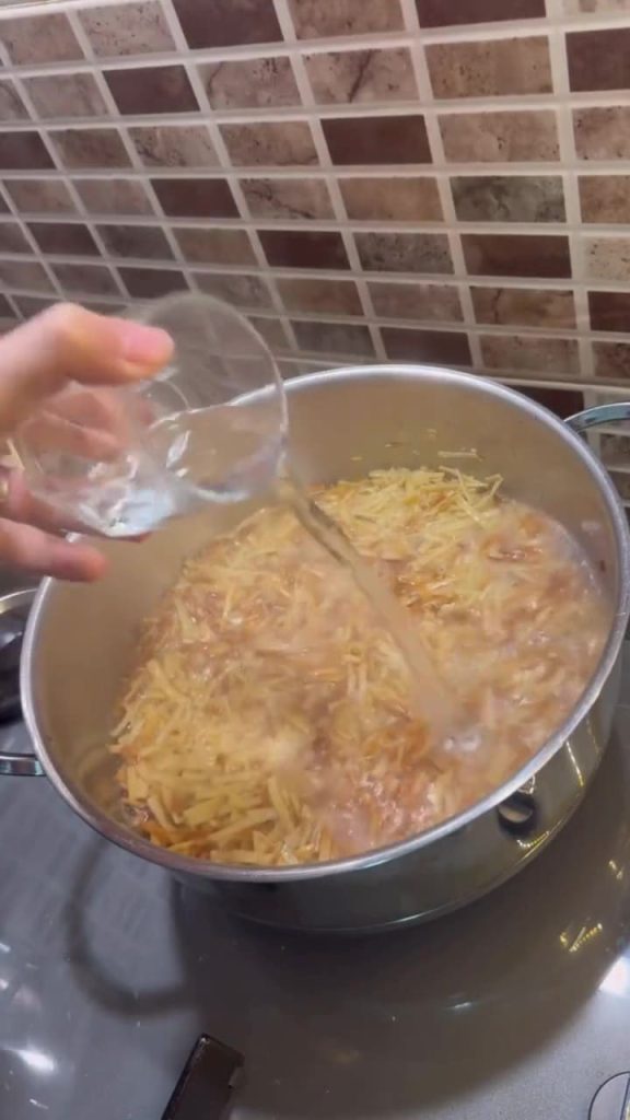 Simmering noodles in hot water on a stovetop.