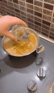 Adding cold water to roasted cornmeal and butter mixture.